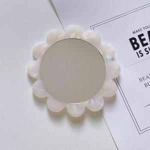 Close-up of pearl white floral acetate mini makeup mirror on a minimalist background