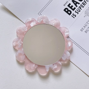 Detail view of pink acetate floral portable makeup mirror on minimalist desk setup