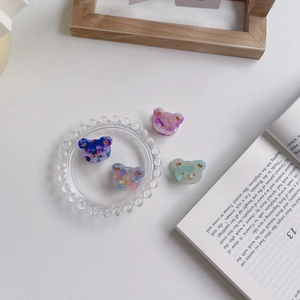 Lot de quatre barrettes ours en acétate coloré bleu, violet et vert sur une assiette