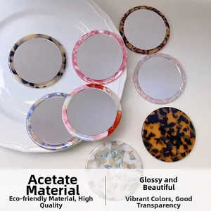 Detail view of round acetate mirrors with tortoise and marble patterns on a white tray