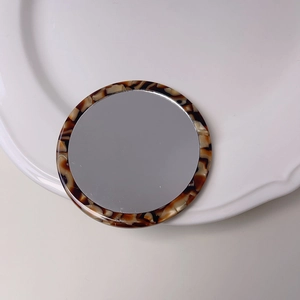 Portable tortoise shell acetate round makeup mirror on a white plate with vintage style