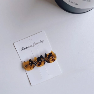 Detail of three tortoiseshell cat hair clips with gold outlines on a jewelry card