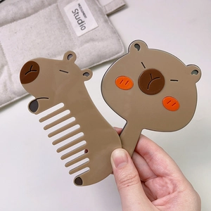 Detail showing hand holding cute cartoon Capybara acetate hair comb and hand mirror set