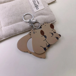 Detailed view of Capybara cartoon keychain accessories on soft quilted fabric