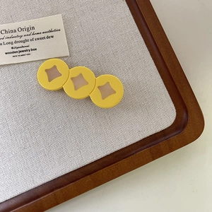 Détail d'une pince à cheveux jaune avec motifs étoiles sur un plateau en bois