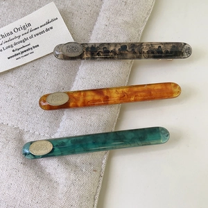Vintage acetate hair clips in grey, amber and emerald with elegant golden metal logo plates