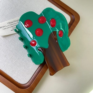 Detailed view of apple tree hair claw made of premium green acetate on a wooden tray