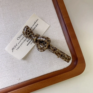 Dettaglio del fermaglio a fiocco in acetato leopardato con chiusura in metallo dorato