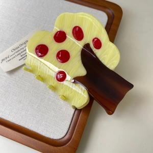 Detailed view of the tree-shaped acetate hair claw clip with red apple accents