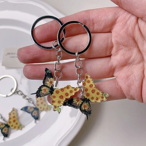 Detailed close-up of acrylic butterfly keychain with bright yellow wings and silver hardware