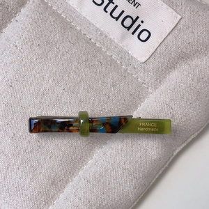 Detail of handmade acetate hair clip with blue tortoiseshell and green resin texture
