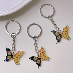 Detailed view of three cute cartoon butterfly keychains with colorful wings on light background