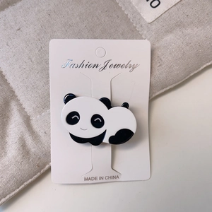Détail d'une mignonne pince à cheveux panda noir et blanc sur carte de présentation