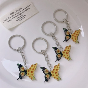 Set of four cute cartoon butterfly keychains with colorful wings on white ceramic plate