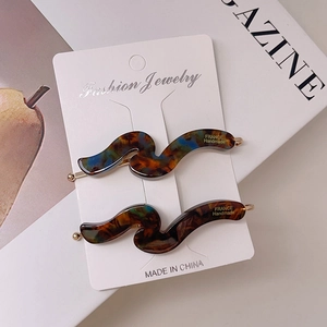 Close-up of wave-shaped tortoiseshell acetate hair clips on a white display card