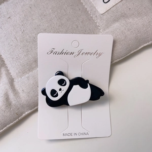 Détail d'une pince à cheveux panda endormi en résine lisse sur une carte d'affichage