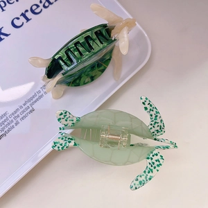 Detail view of turtle-shaped acetate hair claw clips with green marbled patterns