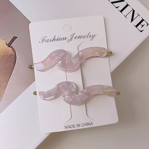 Detail showing two wave-shaped pink marble acetate hair clips on white card holder