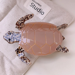 Detailed top view of sea turtle hair claw clip with shell texture and rose pink finish