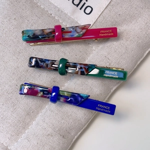 Three-piece acetate bow hair clips in emerald, magenta, and blue with marble texture