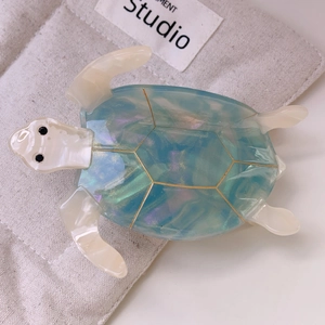 Detail view of the iridescent blue-green turtle shell pattern on a boutique hair claw clip