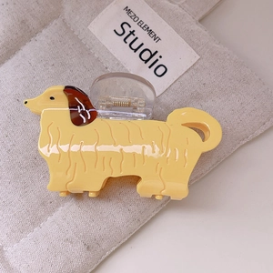 Détail d'une pince à cheveux en forme de teckel mignon avec ressort doré sur tissu