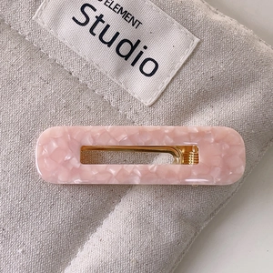 Détail de la pince à cheveux rose marbrée avec attache en métal doré élégante
