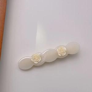 Detailed view of cream white acetate hair clip with 3D rose flowers and wavy edge design