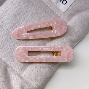 Détails des barrettes en acétate rose marbré avec formes de goutte et de rectangle