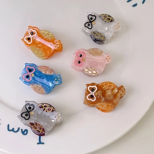 Adorable owl-shaped acetate hair clips in six vibrant colors displayed on a white plate