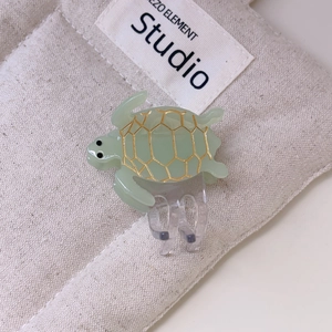 Chic green sea turtle hair claw clip with gold shell patterns for beach styling