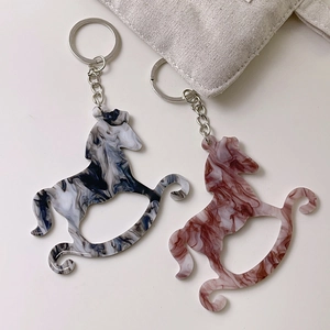 Detail of marble-textured acrylic rocking horse keychains in blue and red tones