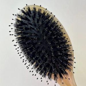 Macro shot of boar bristles and nylon pins on an amber cellulose acetate hairbrush