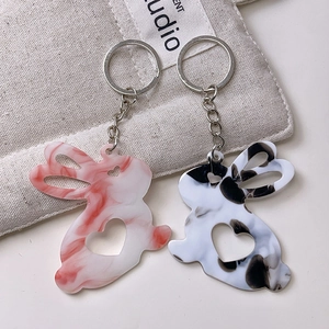 Détail des porte-clés lapin en acrylique marbré avec découpes de cœur sur lin beige