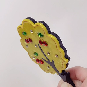 Detail view of a stylish tree-shaped hand mirror with colorful rhinestones and purple base