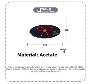 Detailed view of handmade oval acetate hair clip with red rhinestone bow motif