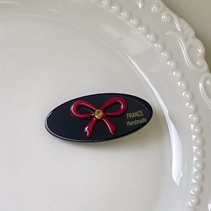 Detail view of rhinestone bow hair clip on elegant pearl-embossed white porcelain plate