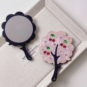 Detailed view of handheld mirrors with pink mica back and cherry rhinestone accents