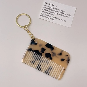 Detailed close-up of a stylish tortoise shell pattern mini comb keychain on white background