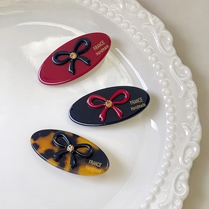 Close-up of three handmade oval rhinestone bow hair clips in burgundy and tortoiseshell