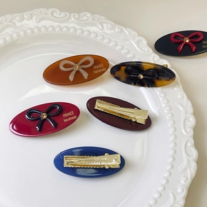 Elegant oval rhinestone bow hair clip set on vintage ceramic tray display