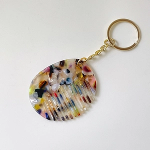 Detailed close-up of a colorful acetate mini comb keychain with artistic tortoiseshell texture