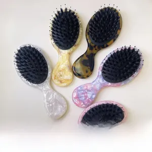 Five assorted colors of acetate hairbrushes showing marble textures and boar bristles