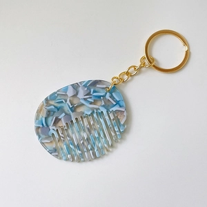 Detail of blue acetate floral mini comb keychain with golden metal ring and chain