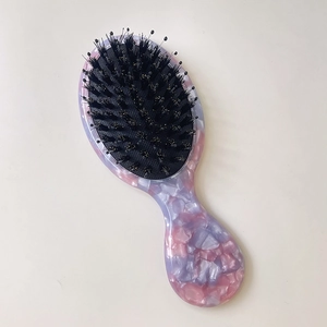 Detail of small pink and purple marbled hairbrush with boar bristles and air cushion