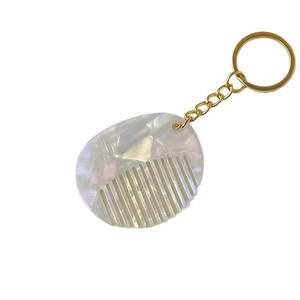 Mini acetate comb keychain with white pearl finish and gold metal ring on white background
