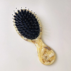 Detailed view of boar bristle and nylon teeth on a marble pattern acetate hairbrush