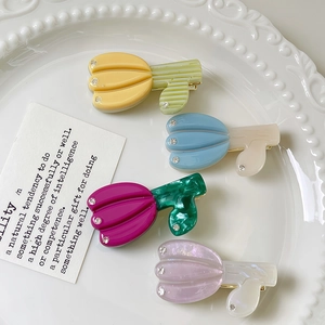 Barrettes tulipe en acétate avec strass disposées sur une assiette en céramique blanche