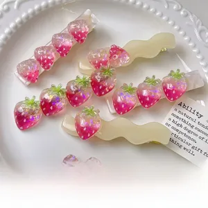 Dettaglio di fermagli per capelli con fragole glitter rosa su forcine in acetato crema