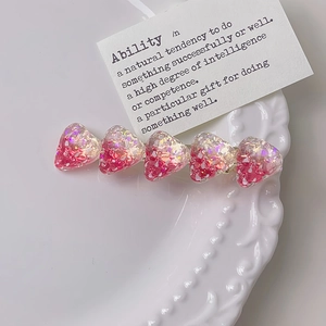 Macro di fermagli per capelli a fragola con glitter rosa su piatto bianco vintage